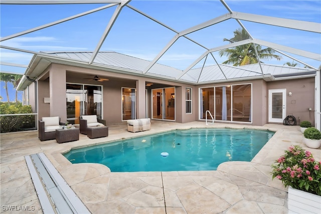 view of pool with outdoor lounge area, ceiling fan, a patio, and glass enclosure