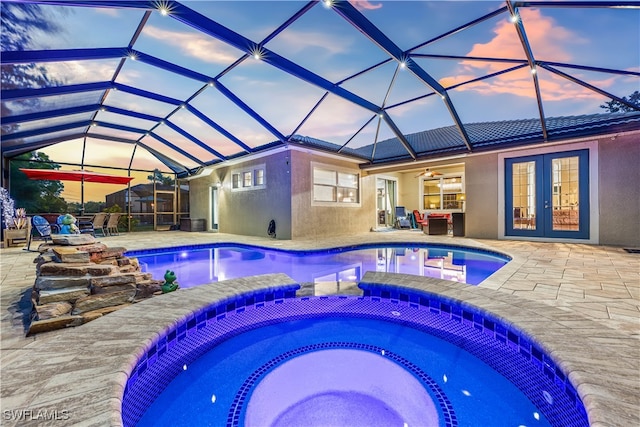 pool at dusk featuring glass enclosure, an in ground hot tub, a patio area, and ceiling fan