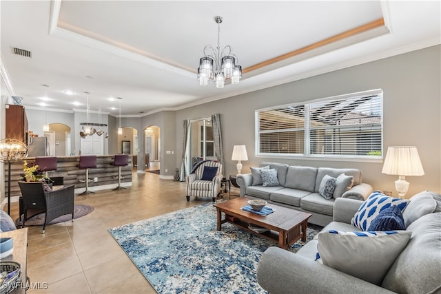 tiled living room with a raised ceiling, a notable chandelier, and ornamental molding