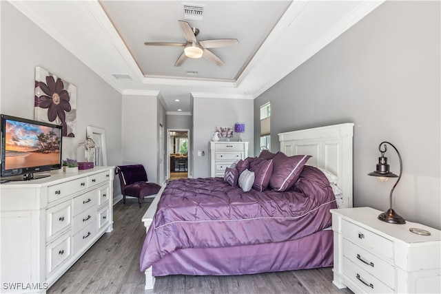 bedroom with hardwood / wood-style floors, ceiling fan, a raised ceiling, and ornamental molding