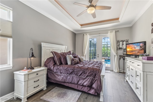 bedroom with ornamental molding, access to outside, a tray ceiling, ceiling fan, and wood-type flooring