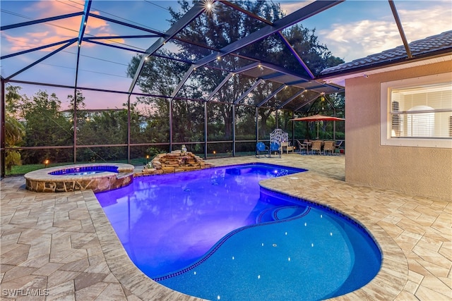 pool at dusk with glass enclosure, a patio area, and an in ground hot tub