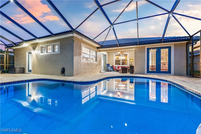 pool at dusk featuring ceiling fan, a lanai, a patio, and french doors