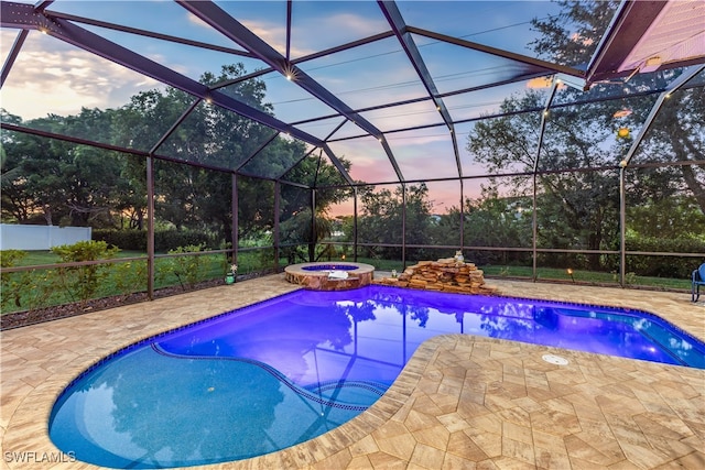 pool at dusk with glass enclosure, an in ground hot tub, and a patio area