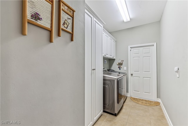 laundry area with cabinets, light tile patterned floors, and washing machine and dryer