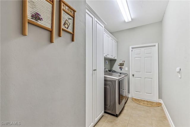 clothes washing area featuring cabinets, independent washer and dryer, and light tile patterned floors