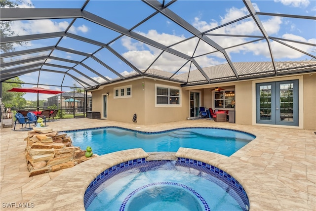 view of pool with glass enclosure, ceiling fan, an in ground hot tub, and a patio