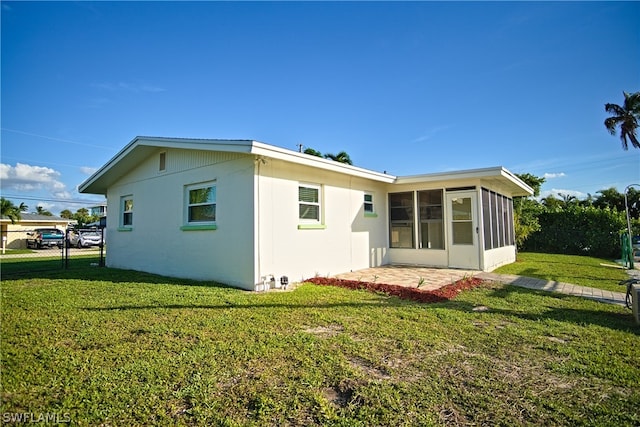 back of property featuring a sunroom and a yard