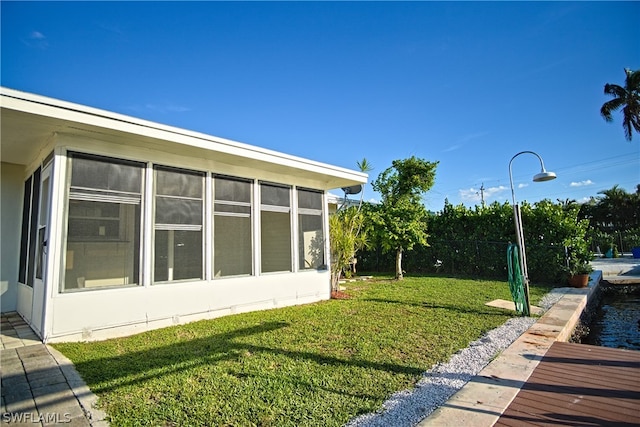 view of home's exterior featuring a sunroom and a lawn