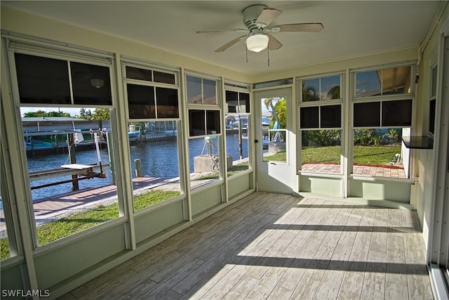 unfurnished sunroom featuring a water view and a ceiling fan