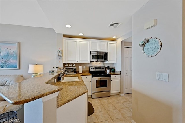 kitchen featuring light stone countertops, sink, kitchen peninsula, white cabinets, and appliances with stainless steel finishes