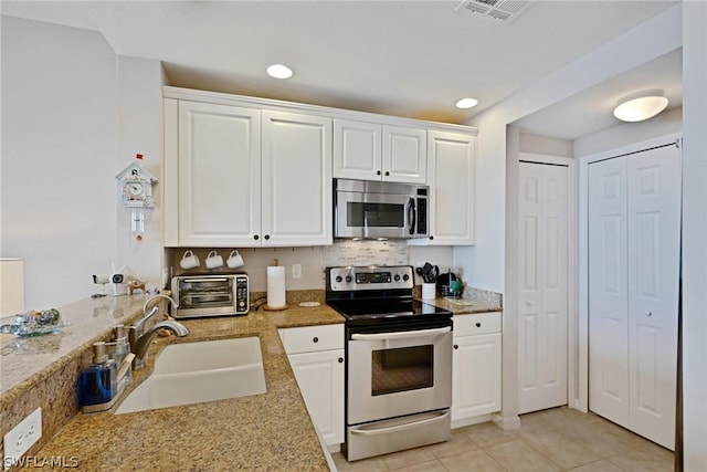 kitchen with white cabinets, sink, decorative backsplash, appliances with stainless steel finishes, and light tile patterned flooring