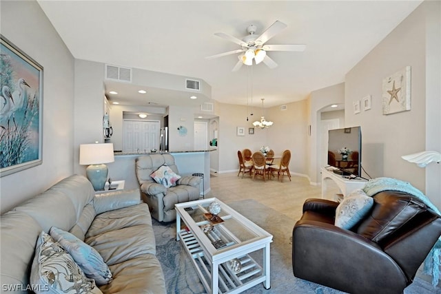 carpeted living room with ceiling fan with notable chandelier