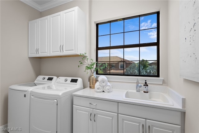 laundry room featuring ornamental molding, sink, washing machine and dryer, and cabinets