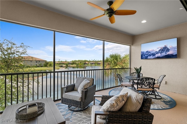 sunroom / solarium featuring a water view and ceiling fan