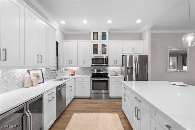 kitchen with sink, appliances with stainless steel finishes, decorative light fixtures, and white cabinets