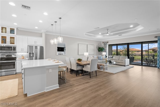 kitchen with a kitchen bar, appliances with stainless steel finishes, light hardwood / wood-style flooring, and white cabinets