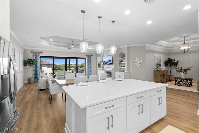 kitchen with light wood-type flooring, stainless steel fridge with ice dispenser, pendant lighting, and white cabinets