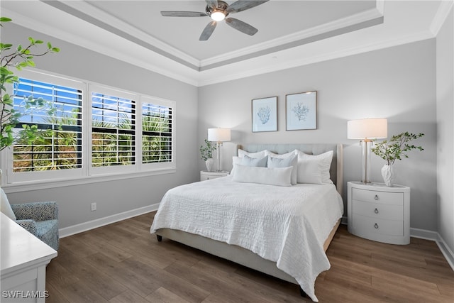 bedroom with ornamental molding, dark hardwood / wood-style floors, a tray ceiling, and ceiling fan