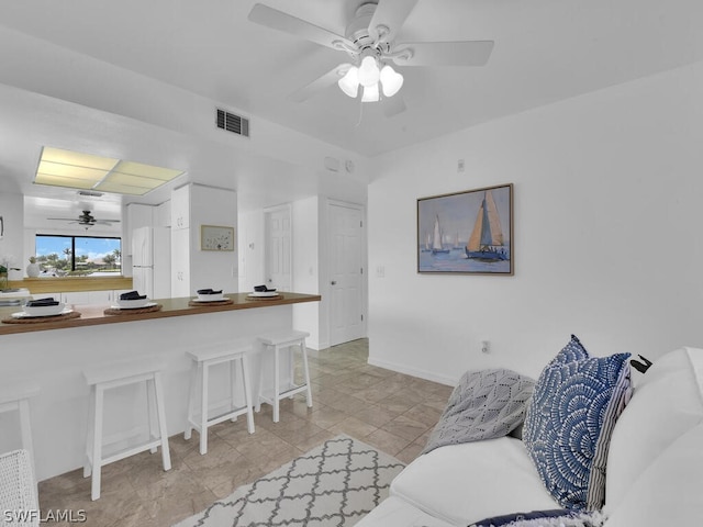 kitchen featuring a kitchen bar, kitchen peninsula, white fridge, and white cabinetry