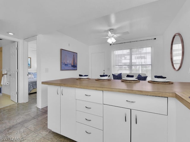 kitchen featuring ceiling fan, wood counters, and white cabinetry