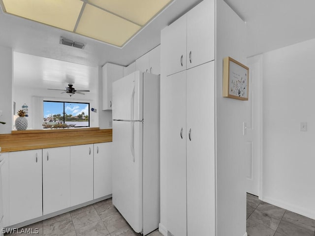 kitchen featuring white cabinets, ceiling fan, and white fridge