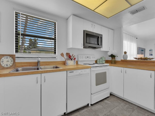 kitchen featuring white appliances, white cabinetry, and sink