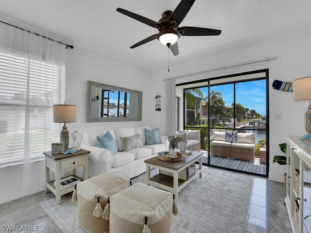 living room featuring ceiling fan and a water view