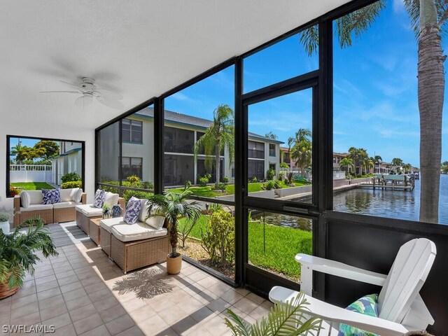 sunroom with ceiling fan and a water view