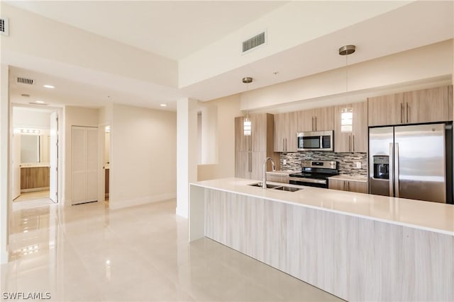 kitchen with hanging light fixtures, backsplash, appliances with stainless steel finishes, and light brown cabinets