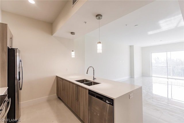 kitchen featuring kitchen peninsula, appliances with stainless steel finishes, sink, and pendant lighting