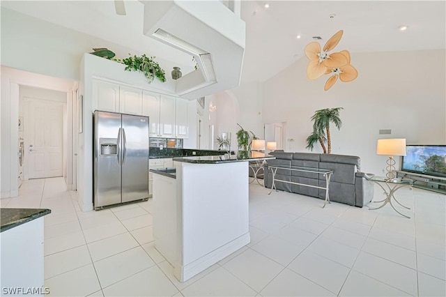 kitchen with dark countertops, stainless steel fridge, white cabinets, and light tile patterned flooring