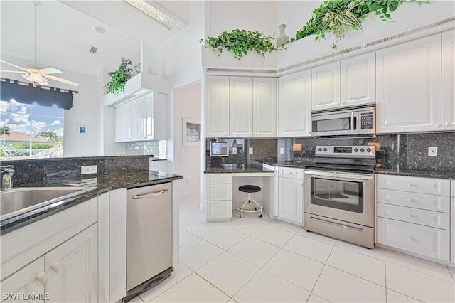 kitchen with appliances with stainless steel finishes, dark stone countertops, white cabinetry, and decorative backsplash