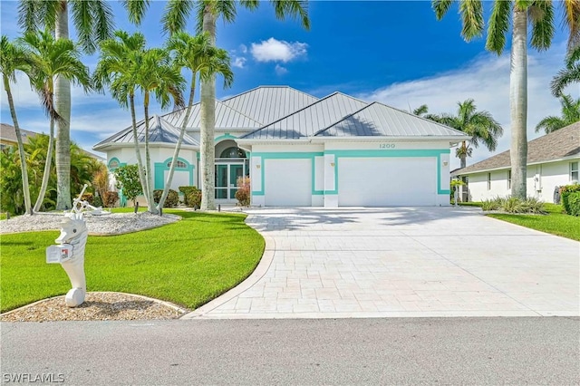 ranch-style home with a garage, metal roof, a standing seam roof, decorative driveway, and a front lawn