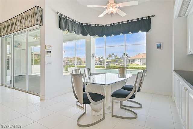 dining space featuring light tile patterned floors, a ceiling fan, and baseboards