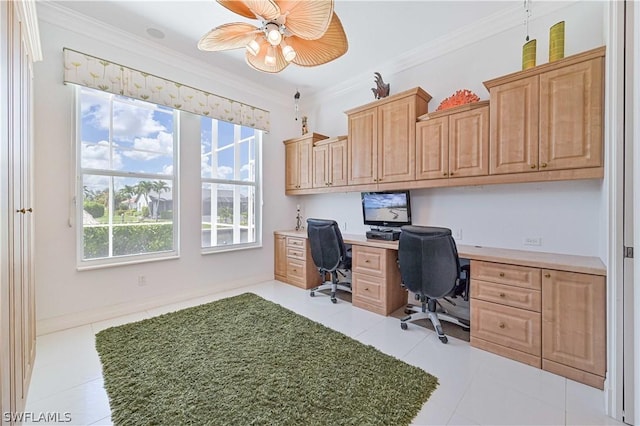 home office featuring built in desk, light tile patterned floors, ornamental molding, ceiling fan, and baseboards