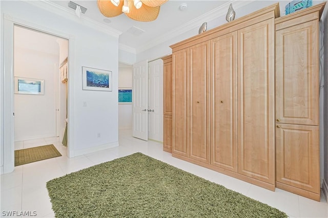 interior space with light tile patterned floors, a ceiling fan, visible vents, baseboards, and ornamental molding