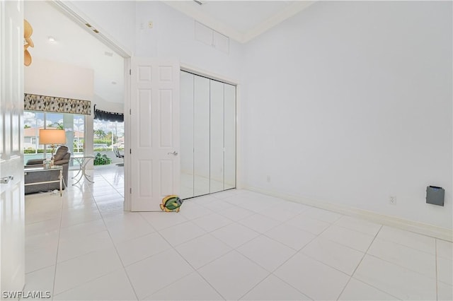 interior space featuring light tile patterned flooring, a towering ceiling, and baseboards