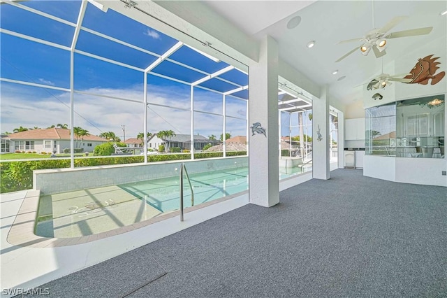 outdoor pool with glass enclosure, ceiling fan, a patio area, and a residential view