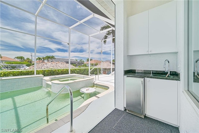 exterior space with dark countertops, a sunroom, white cabinetry, a sink, and high end refrigerator