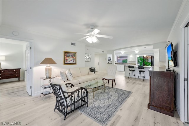 living room featuring ceiling fan, light hardwood / wood-style floors, and ornamental molding