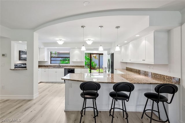 kitchen featuring white cabinetry, hanging light fixtures, light stone counters, kitchen peninsula, and black appliances