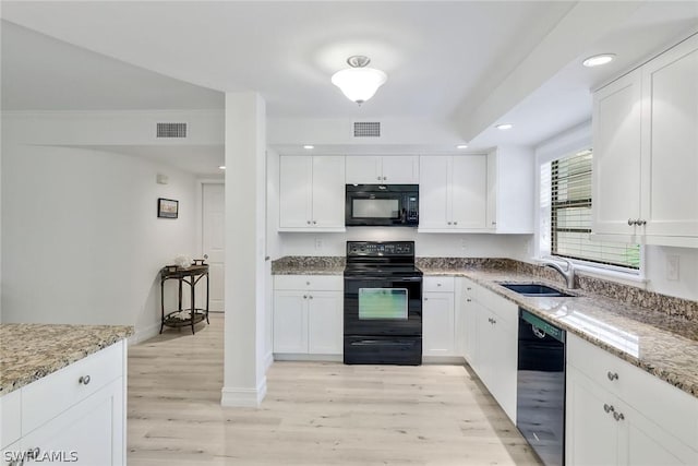 kitchen featuring light stone counters, sink, white cabinets, and black appliances