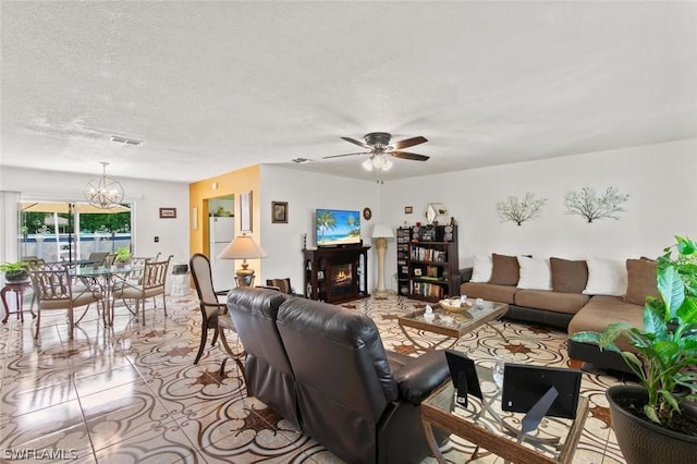 living room featuring ceiling fan with notable chandelier, light tile patterned floors, and a textured ceiling