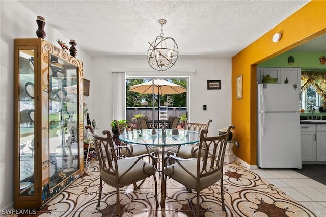 tiled dining space featuring sink, a textured ceiling, and a notable chandelier