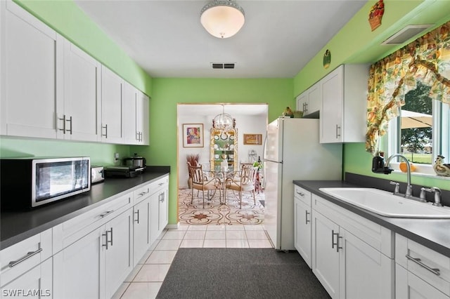 kitchen featuring white cabinets, sink, hanging light fixtures, light tile patterned floors, and white fridge