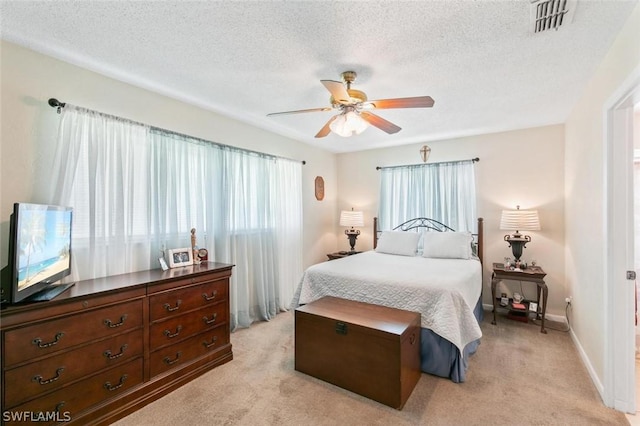 bedroom featuring ceiling fan, light colored carpet, and a textured ceiling