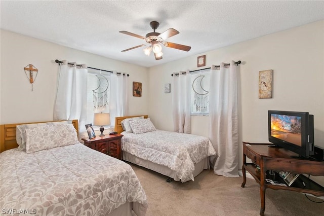 carpeted bedroom featuring ceiling fan and a textured ceiling