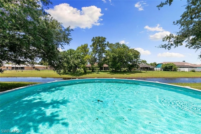 view of pool with a yard and a water view