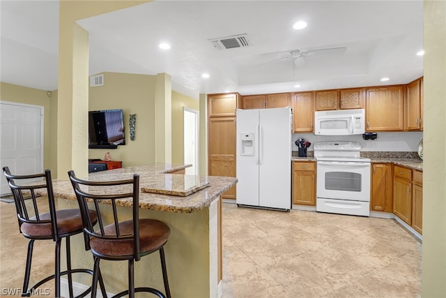 kitchen featuring light tile floors, white appliances, ceiling fan, and a kitchen bar